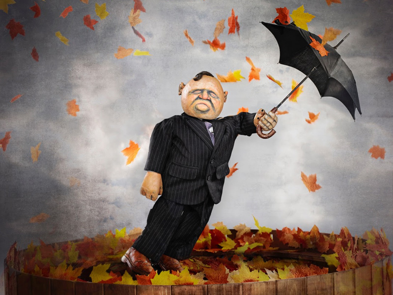 A puppet with an umbrella and blowing leaves