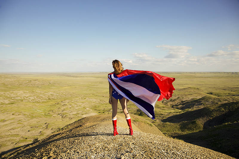 A photo of a woman standing on the prarie wearing a cape