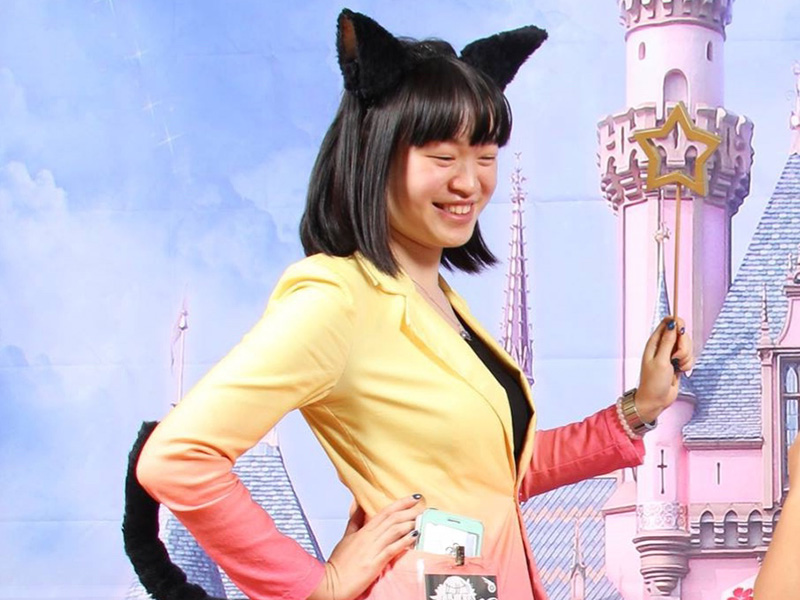 Achiru Wong wearing cat ears and a tail while holding a magic wand