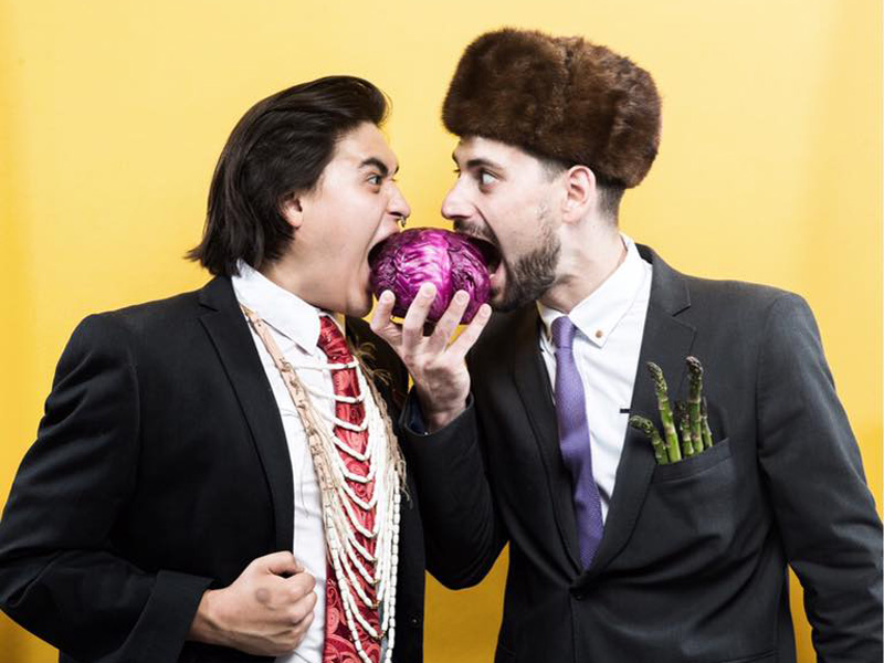 Two men bite into a red cabbage.