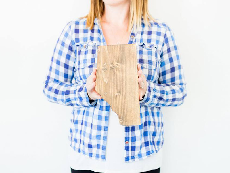 A woman hold an Alberta shaped wood cutout