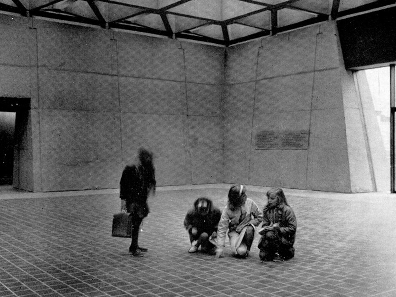 Black and white photo of four people in a large room