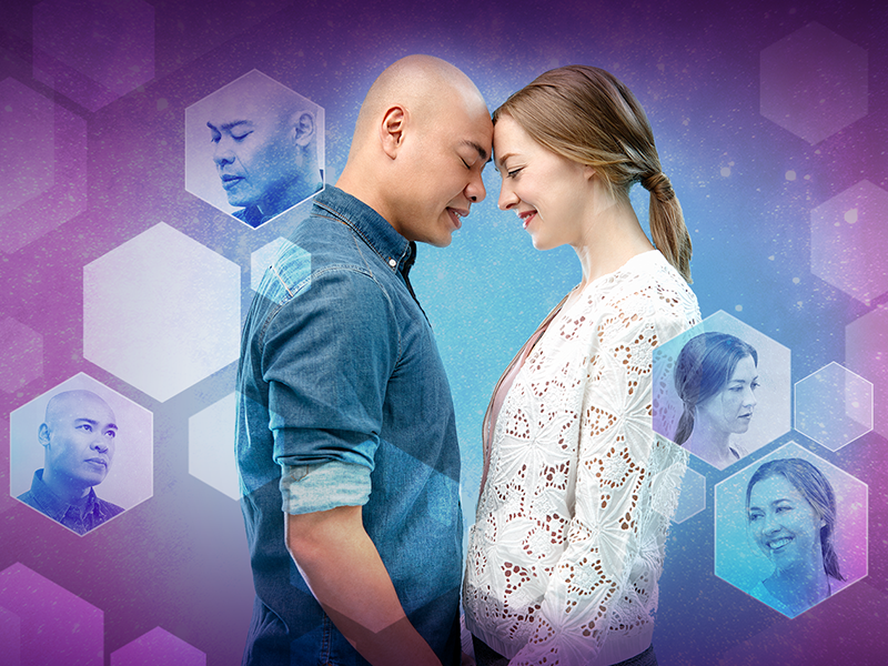 A man and a woman stand touching foreheads and holding hands