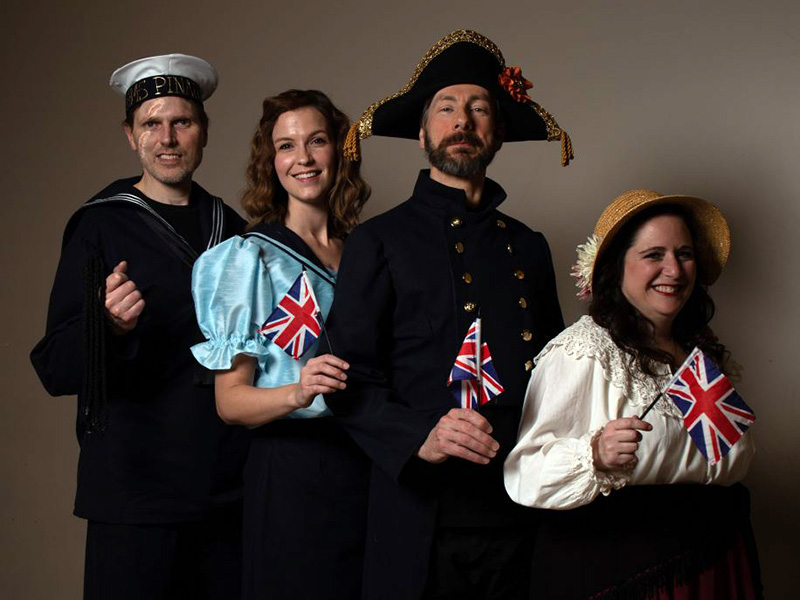 Photo of Steve Hansen Smythe, Jennifer Michaud, George Thomson, and Tracy Smith in costume, each holding a Union Jack flag
