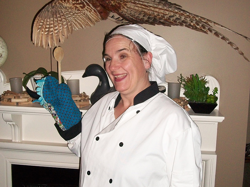 A woman in a chef's uniform holding a wooden spoon