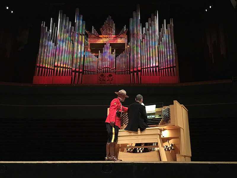 Photo of an organ lit up and a Mountie next to a performer