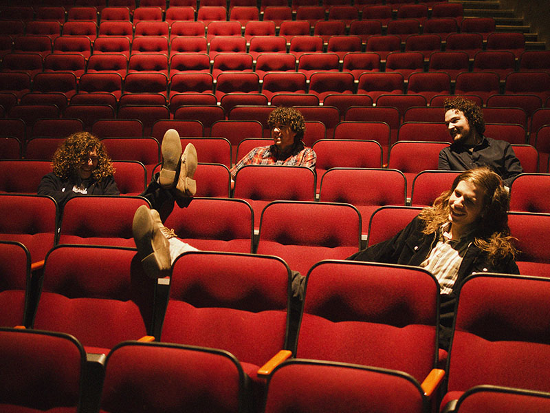 Promo photo of Mother Sun in an empty theatre lounging on red velvet theatre seats