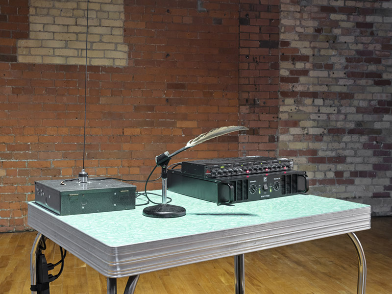 Recording equipment sits on a blue laminate table top in front of a brick wall