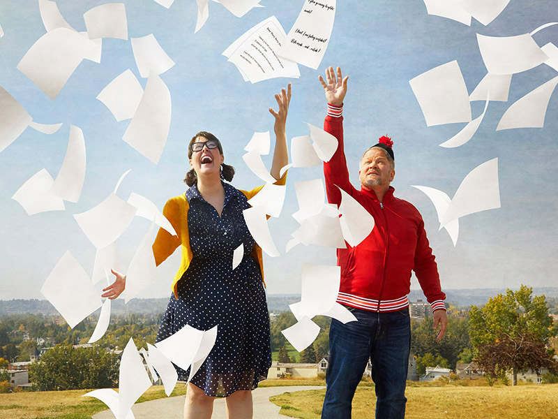A girl and a man throw letters into the air
