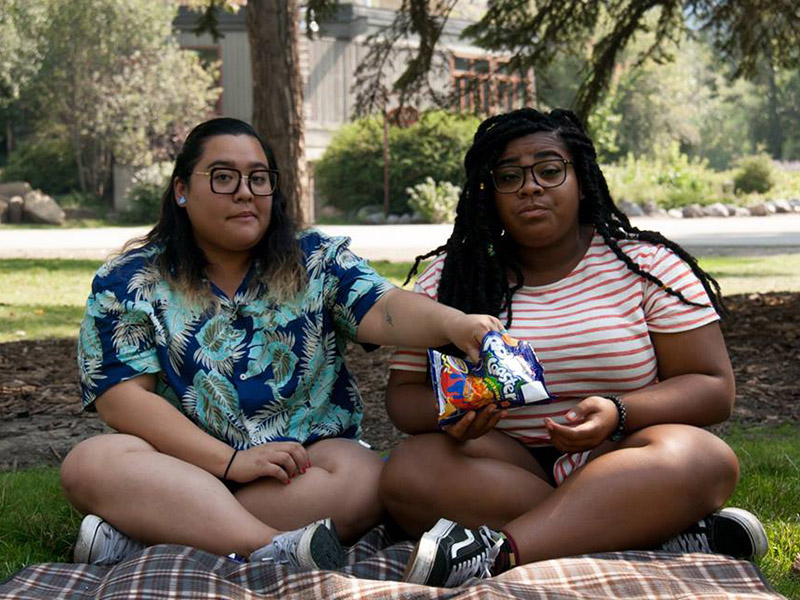 Bianca Miranda and Keshia Cheesman sit on a picnic blanket