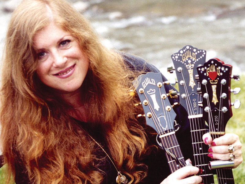 A photo of Ellen McIlwaine holding three guitars