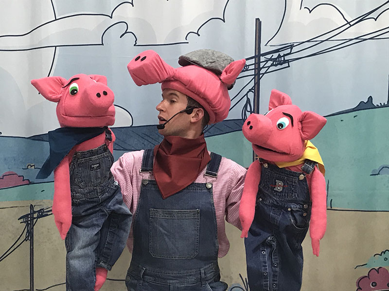 A puppeteer controls two pigs in Evergreen Theatre's production of The Three Little Pigs and B.B. Wolfe