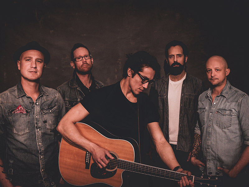 A promotional image of The Prairie States with one band member holding an acoustic guitar