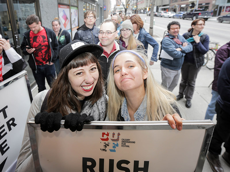 Two people stand behind the rush line sign at the Calgary Underground Film Festival