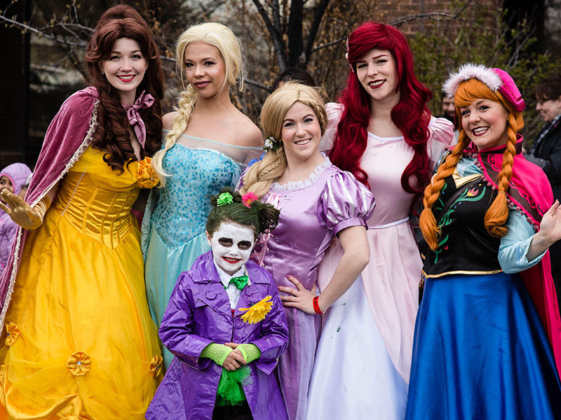 Cosplayers dressed as Disney princesses, and one little Joker, take part in the POW! Parade of Wonders