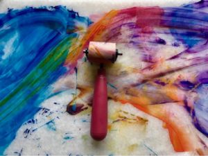 Photo of paint roller on top of abstract painting