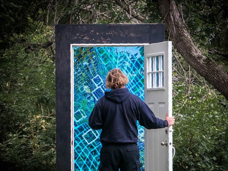 An image of person about to walk through a door in the middle of a park