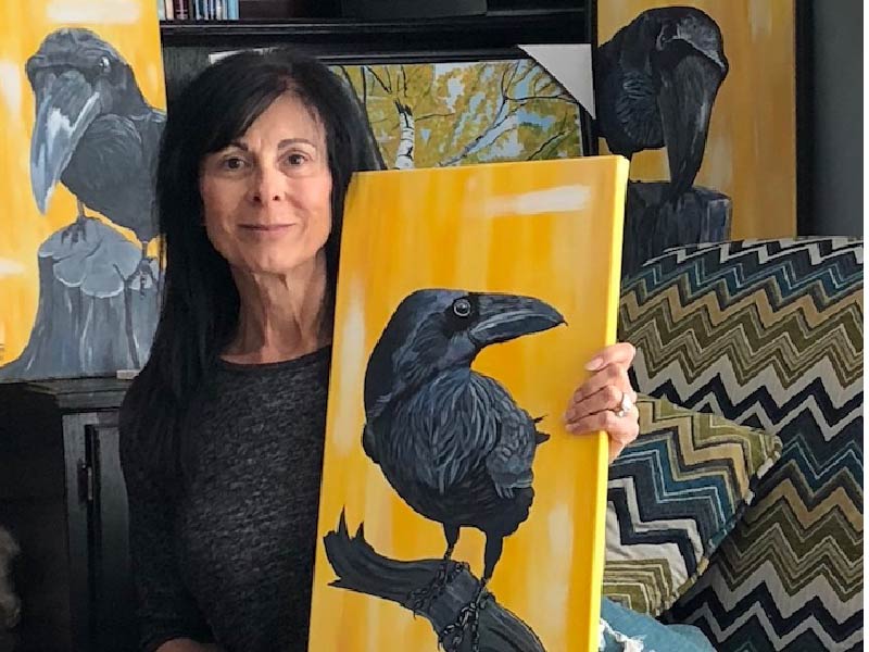 A photo of Sheila Lee holding her painting of a bird