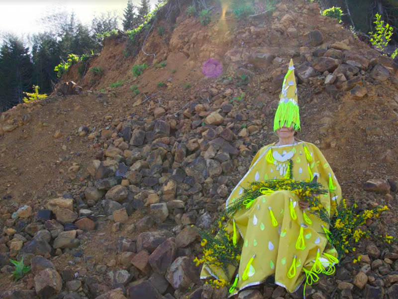 A person wears a yellow costume on a rocky hill