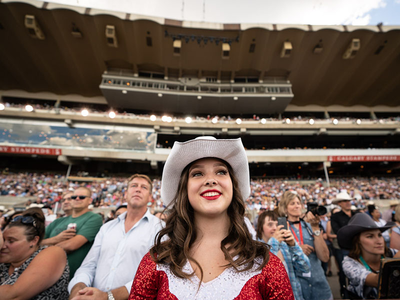 A performer in a glittering outfit stands in the Grandstand crowd