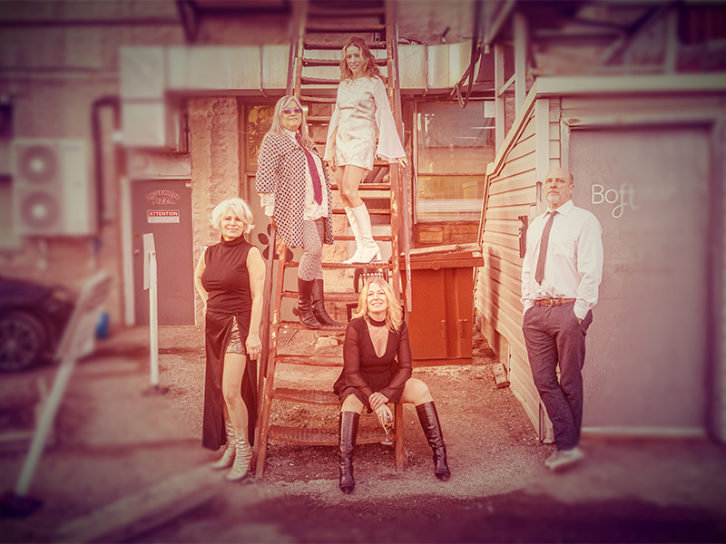 Five people standing on and against a staircase at the back of a building