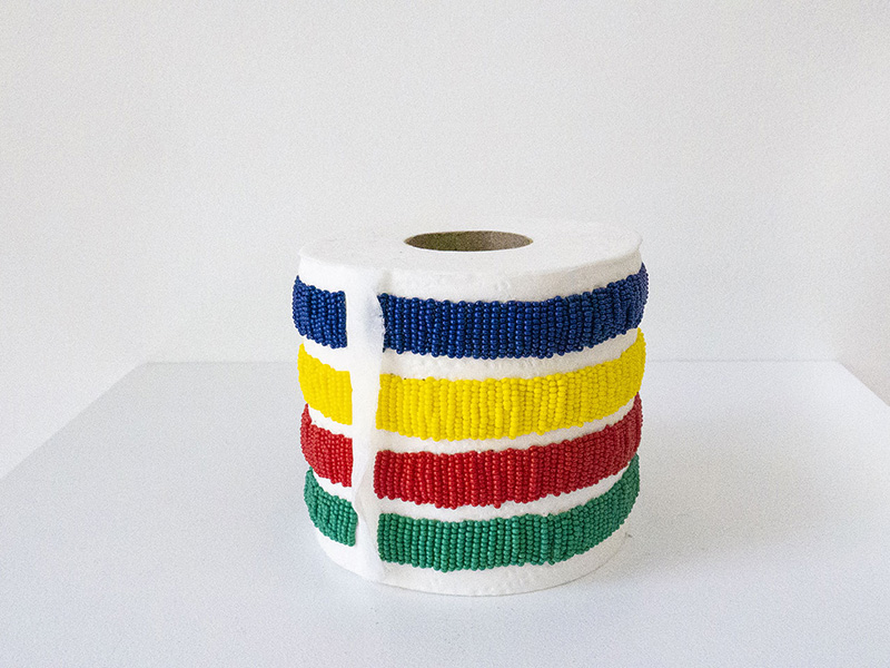 A toilet paper roll beaded in blue, yellow, red and green stripes