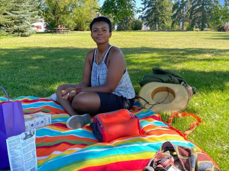 Stephanie Solomon sitting on a picnic blanket on a sunny summer day