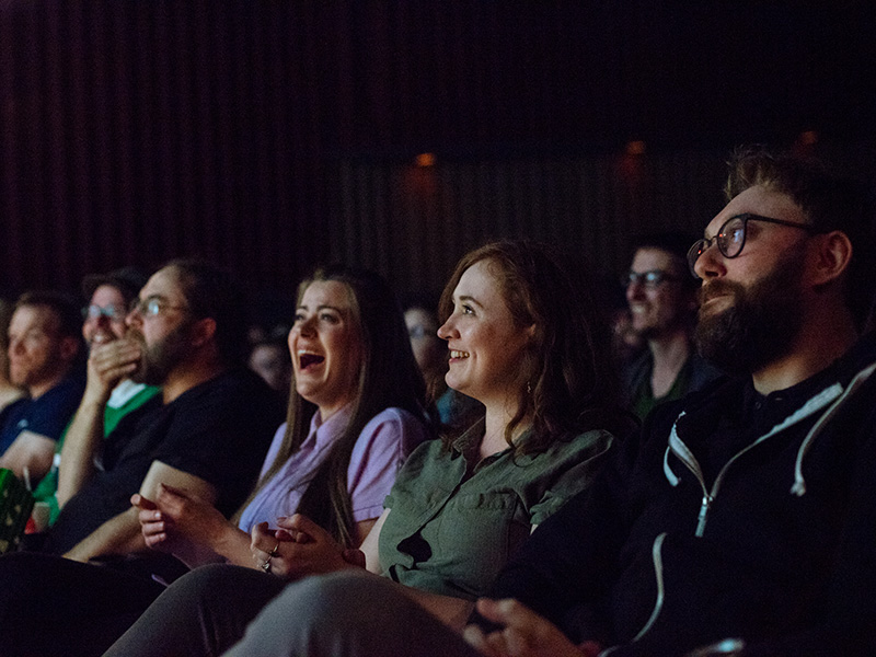 Audience members laughing in a theatre