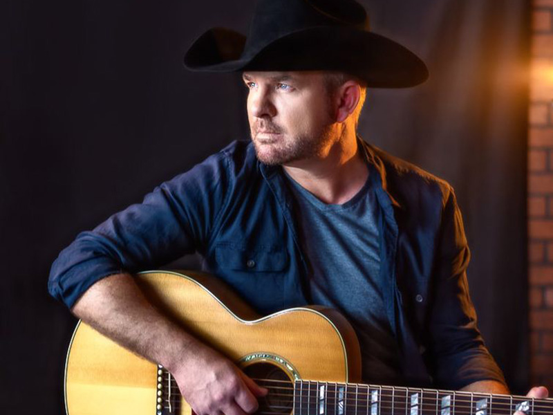 A promo photo of Bobby Wills in a cowboy hat with a guitar