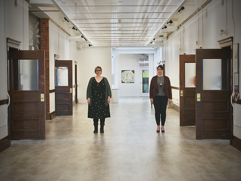 Two women in a school hallway with the doors around them all open