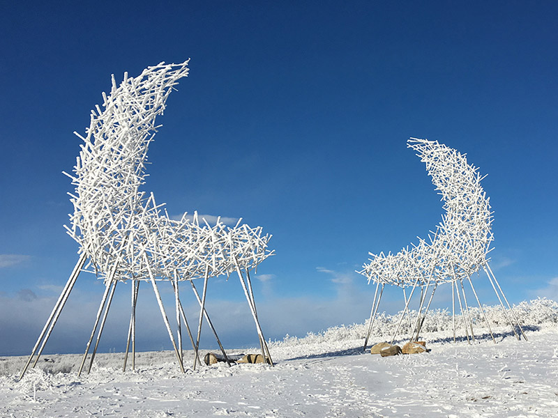 Two large white sculptures in a snowy field