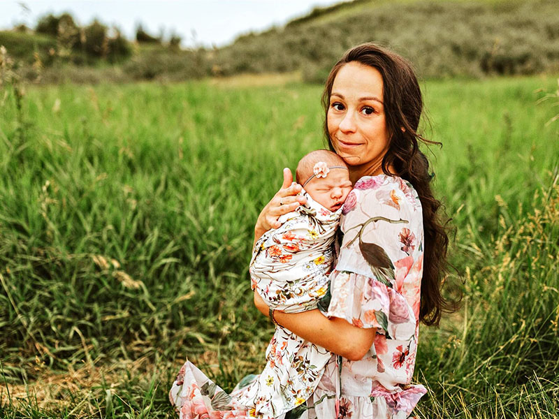 Agnes Chen holds her baby in a green field