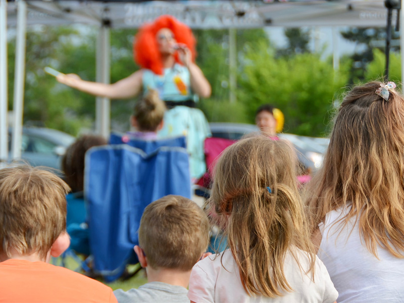 Children watch a performer at an outdoor pop-up ArtsXpeditions show