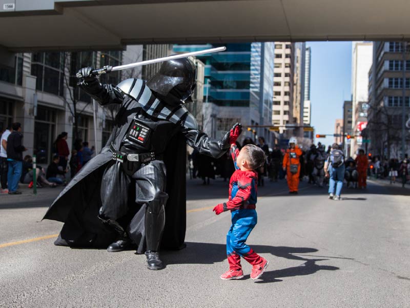 Image of Darth Vader cosplayer high-fiving a kid in Spiderman costume