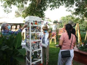 Image of people browsing art for purchase in a garden setting