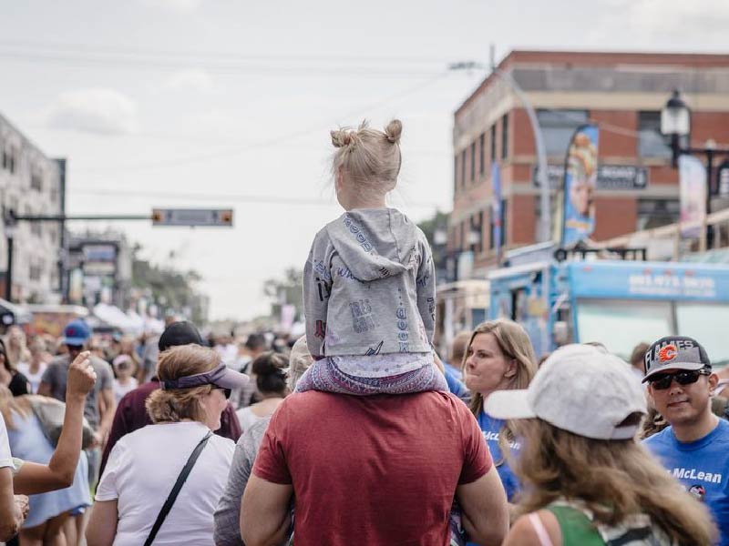 A child rides through the Inglewood Sunfest crowd on a person's shoulders