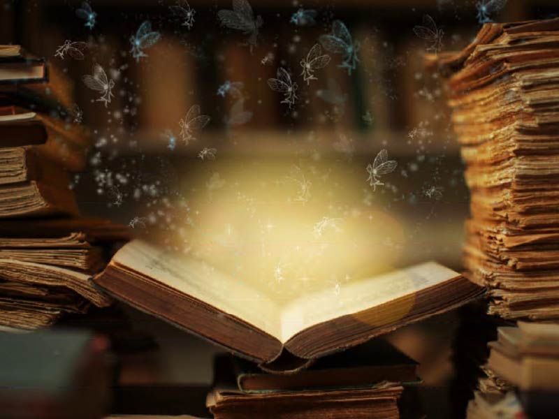 Image of an open "magical" book with particles floating out of it
