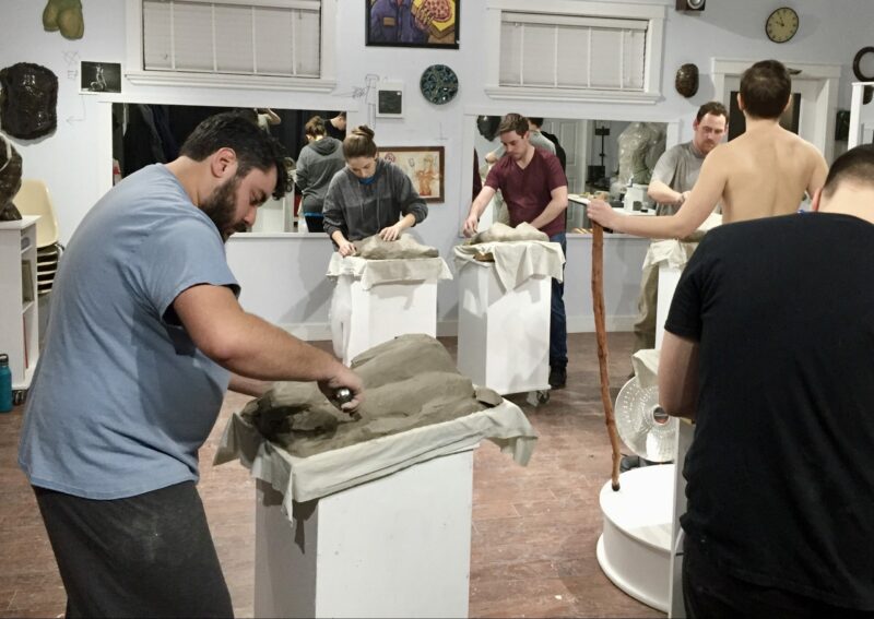 Attendees of the workshop for live model sculpting, practicing their skills in a studio.