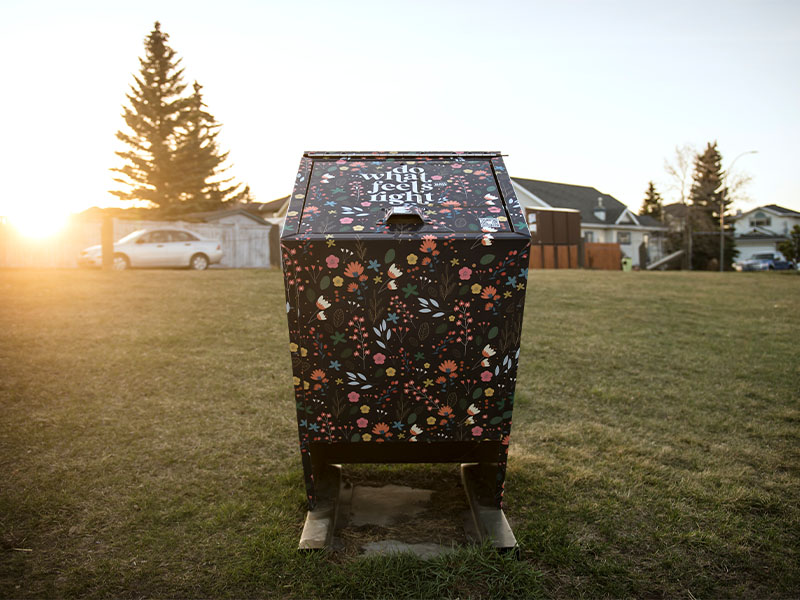 A garbage bin decorated with flowers and the words "Do what feels right"