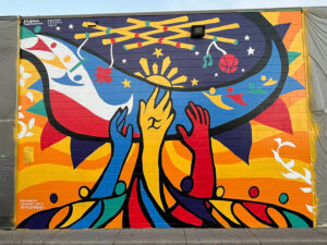 Multicoloured hands reach to the stars in a colourful mural.