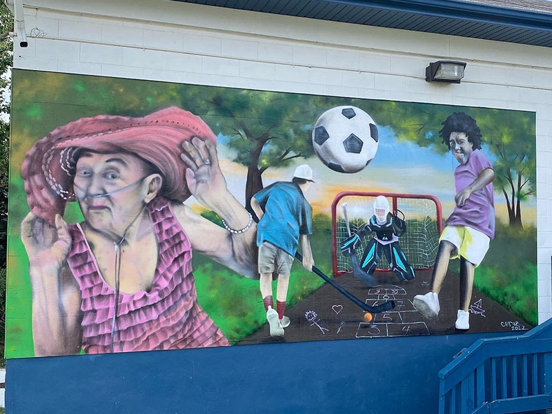 Community members are painted onto the wall of the Mount Pleasant Community Association in an abstract and whimsical style.
