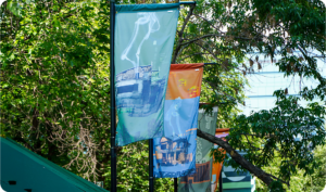 Colourful banners in front of bright green foliage along a public street or bridge