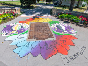 A sidewalk mural of flowers and next to a park