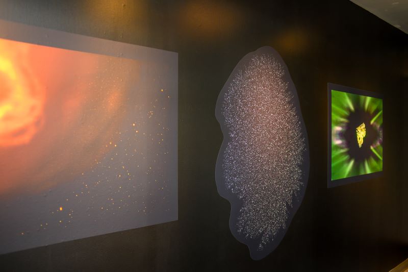 Artistic prints of lights against the night sky, in oranges and greens, hang on a wall.