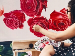Person painting roses on a large canvas