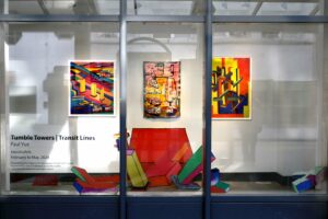 Through a glass door and windows we see three wall-mounted artworks and free standing sculptures in bold colours.