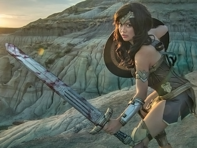 Gladzy Kei poses in cosplay against a sunset landscape