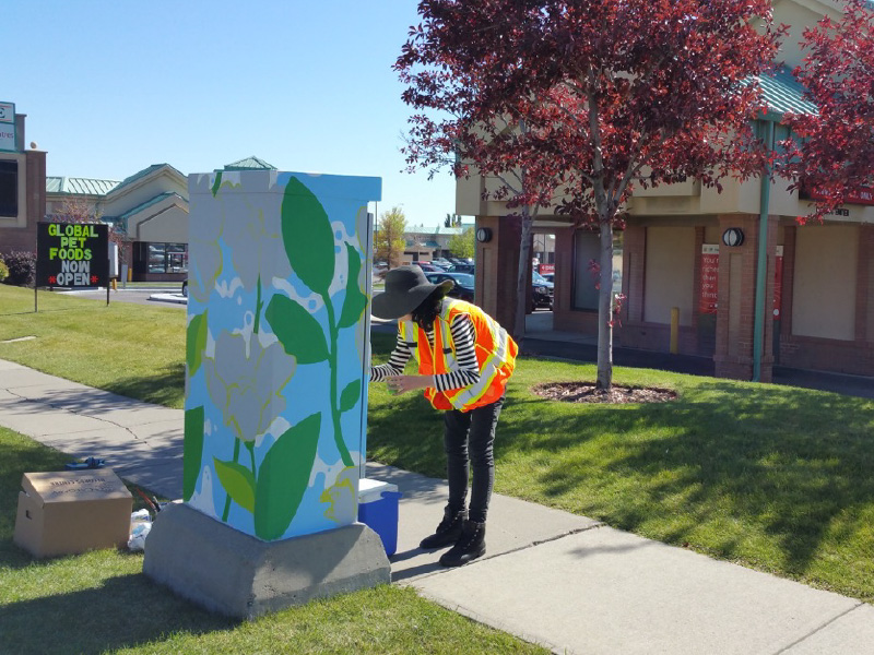 Person in safety vest leans towards painted utility box