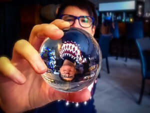 Person holding a glass ball showing himself upside down