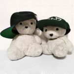 Two teddy bears wearing ball caps